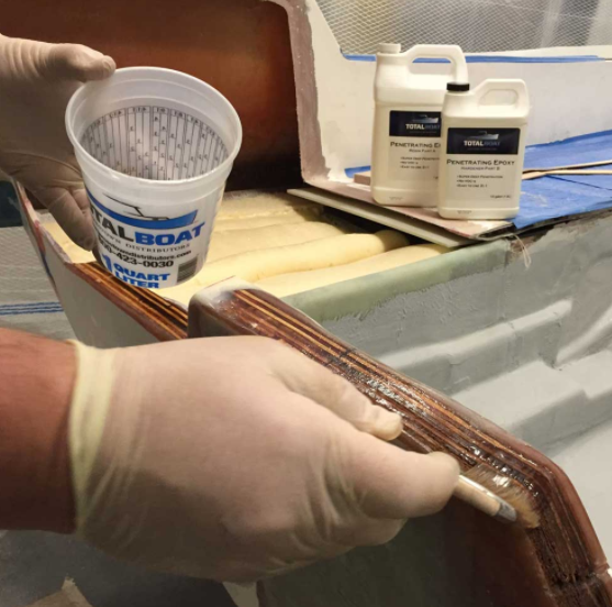 Applying TotalBoat Penetrating Epoxy to a wooden transom on a boat