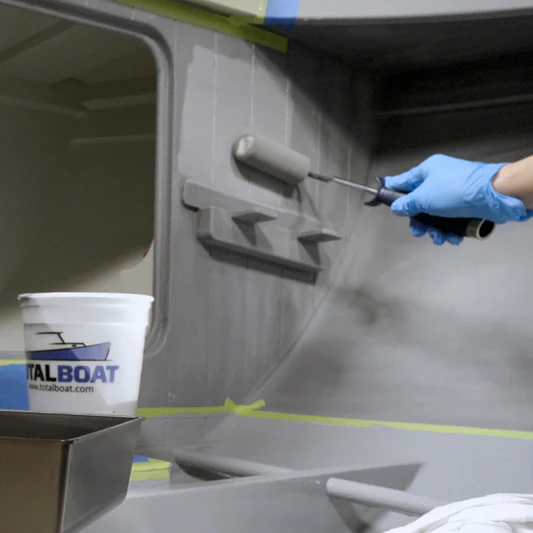 Topside primer being applied with a roller by man wearing protective gloves