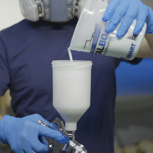 Man pouring thinned topside boat paint into spray gun applicator