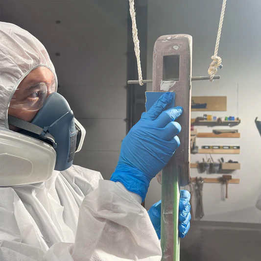 Person in protective gear sanding down polyester fairing compound