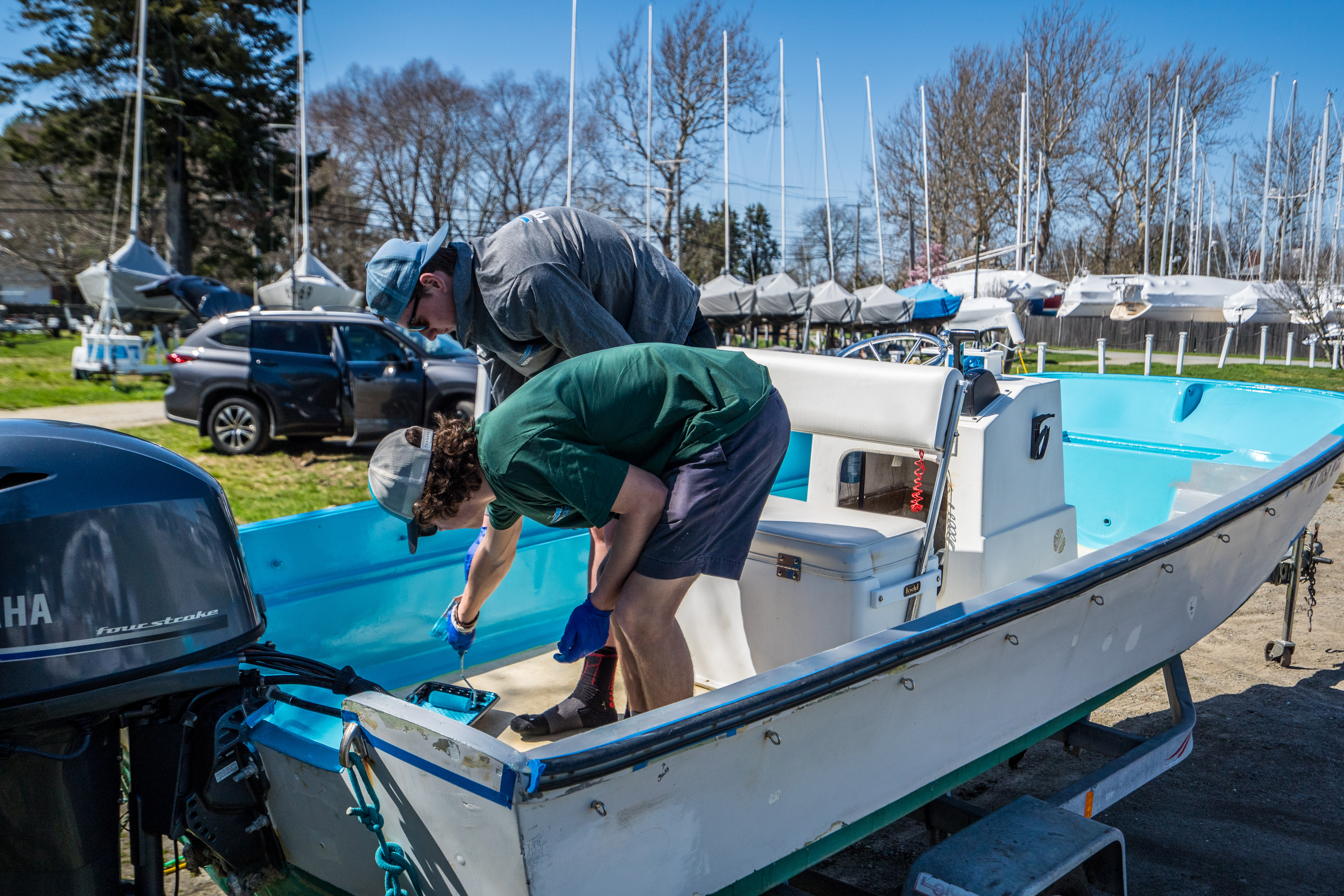 Two men using roll and tip method to apply TotalBoat Wet Edge boat paint on deck and hull