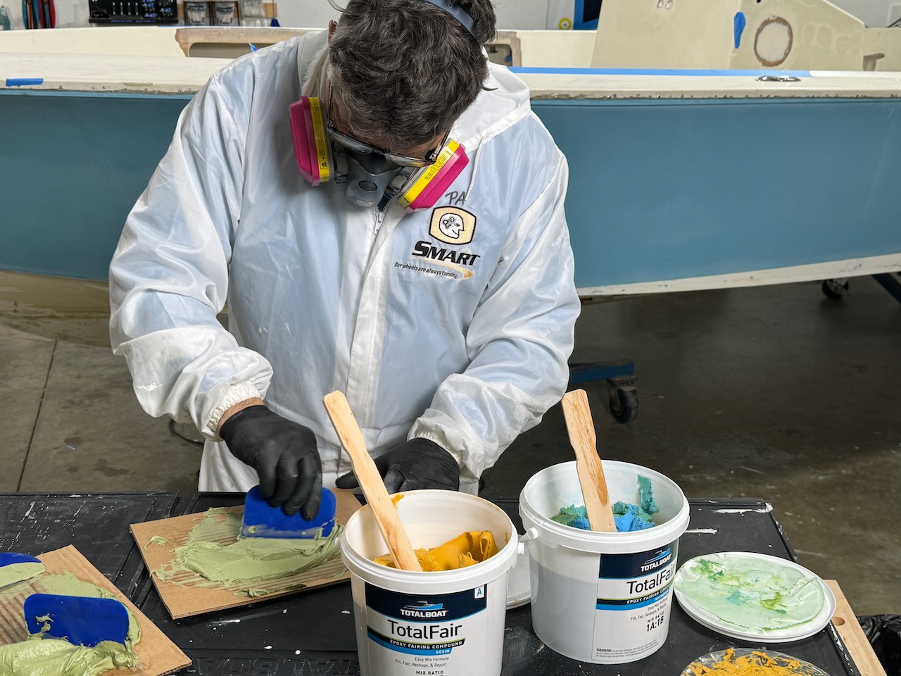 Man wearing protective gear mixing TotalBoat TotalFair epoxy fairing compound components