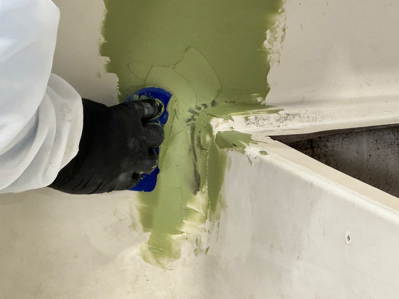 Close up of person applying TotalBoat fairing compound on boat with spreader