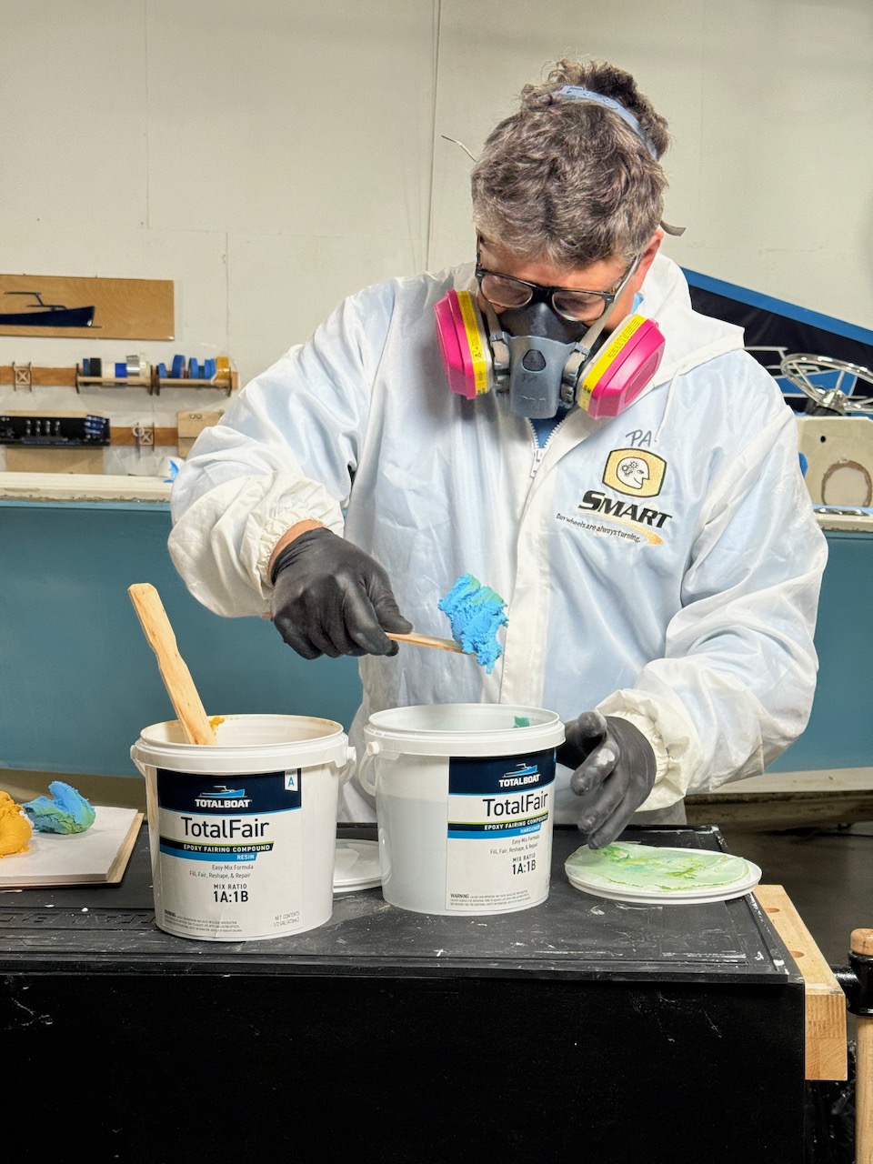 Man wearing protecting equipment mixing TotalBoat TotalFair fairing compound components