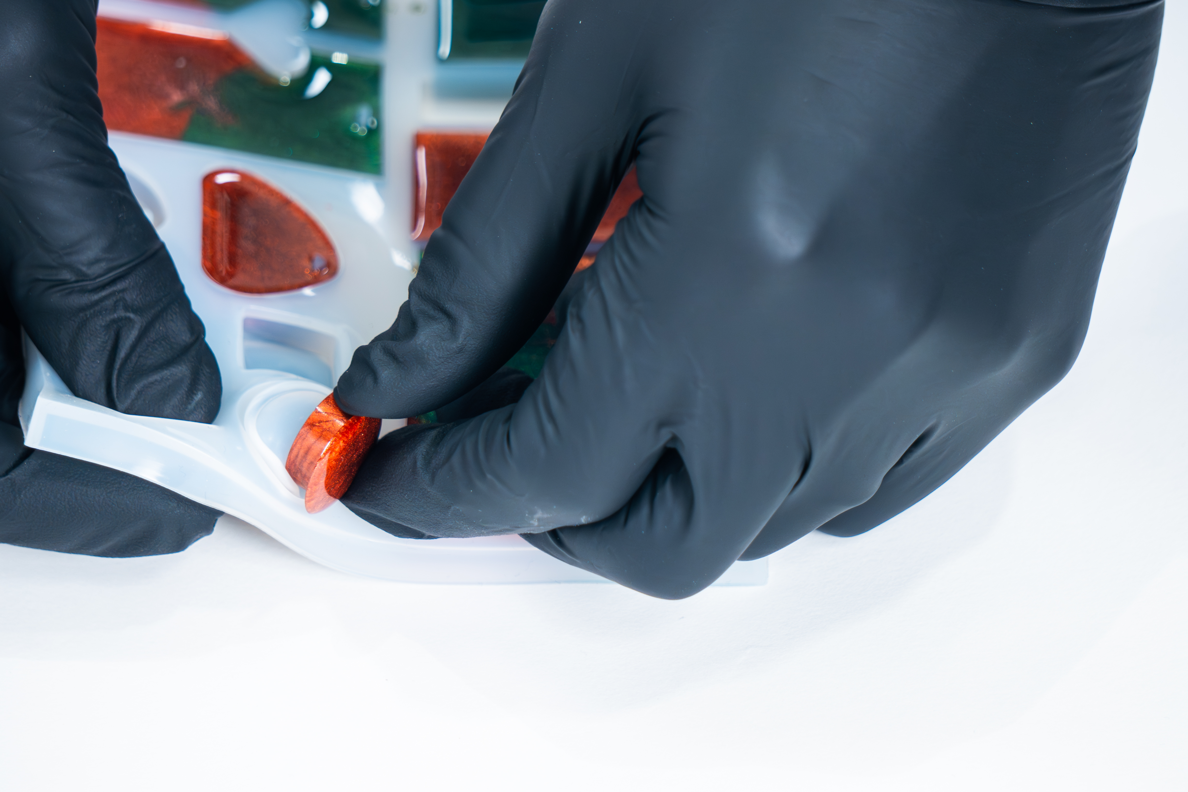 Person wearing gloves removing epoxy resin charm from mold