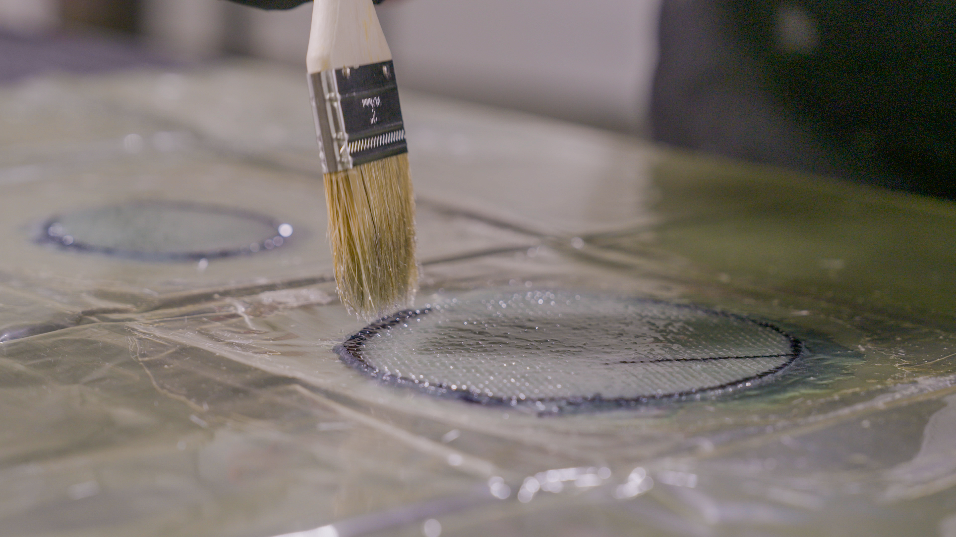 Chip brush applying polyester resin on fiberglass lamination for boat repair
